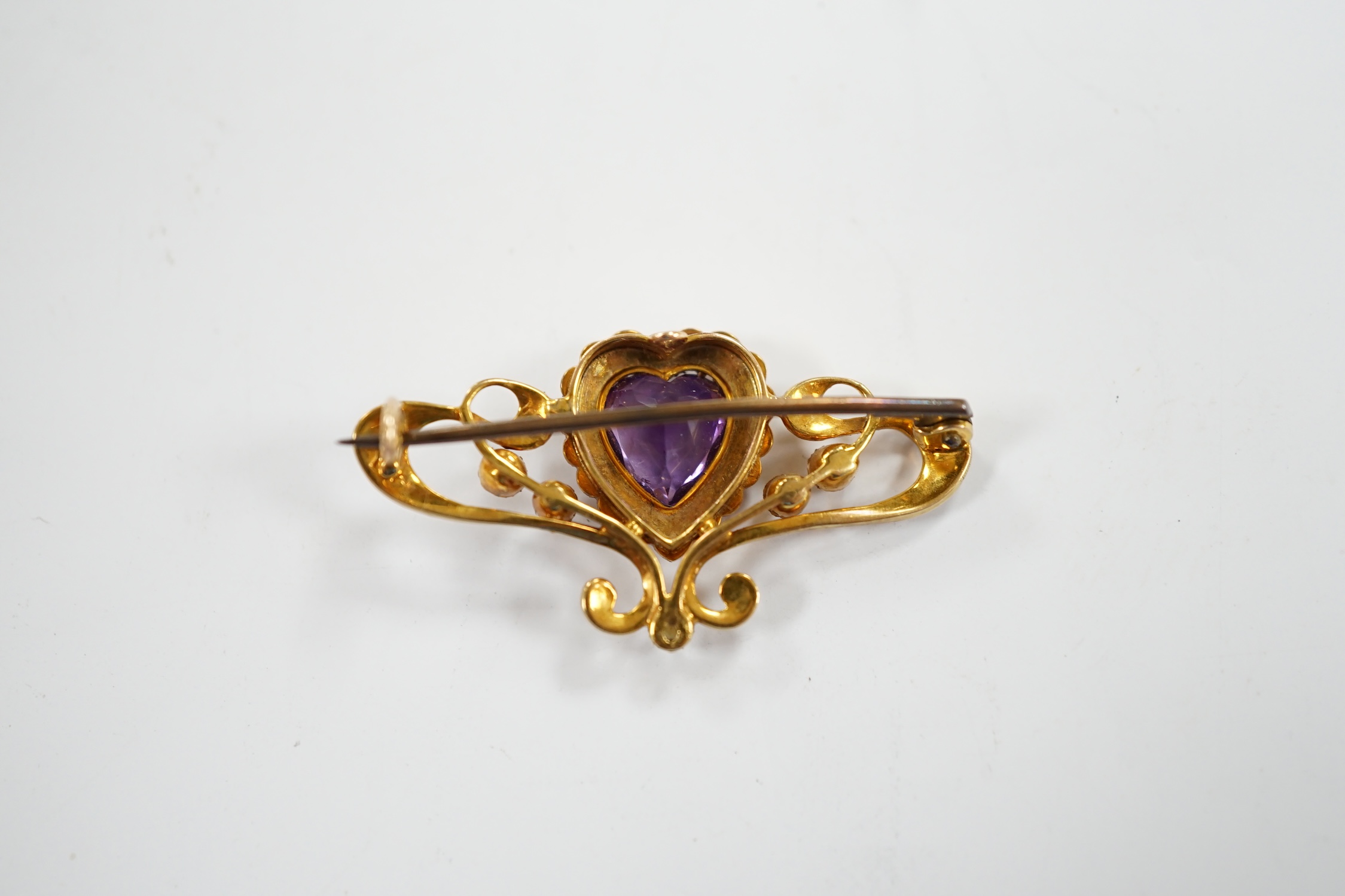 An Edwardian 15ct?, amethyst and seed pearl cluster set bar brooch, with central heart motif, 38mm, gross weight 4.7 grams.